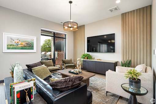 A living room with a black couch and a green vase on a coffee table.
