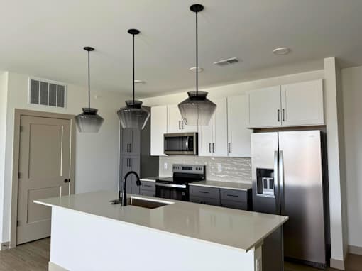 A kitchen with a white counter top and stainless steel appliances.