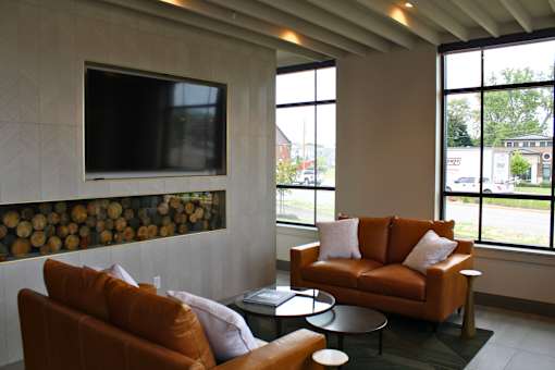 A living room with a brown couch and a television mounted on the wall.