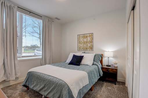 A bedroom with a bed, nightstand, and window.