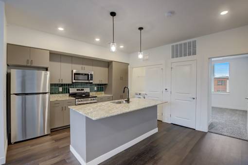 A modern kitchen with a stainless steel refrigerator and a marble countertop.