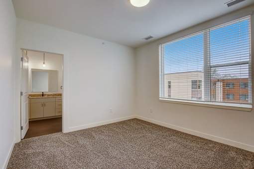 A room with a carpeted floor and a window with blinds.
