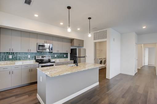 A modern kitchen with a marble countertop and stainless steel appliances.