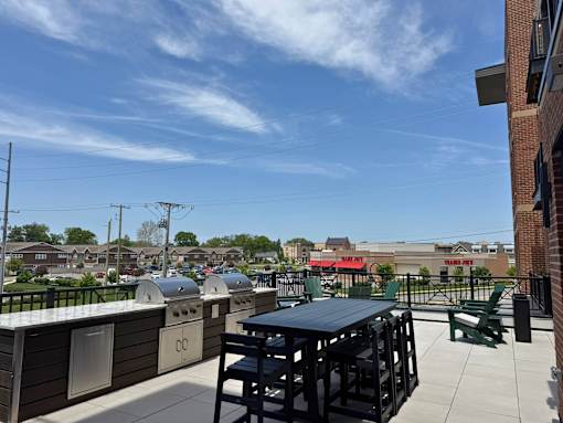 A rooftop patio with a black table and chairs.