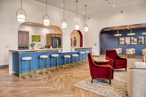 A blue bar with stools and a red chair in front of it.