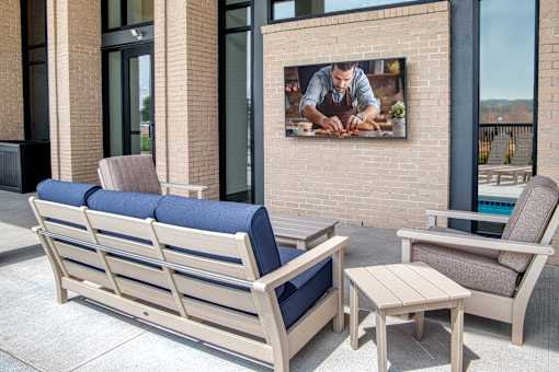 A wooden bench with a blue cushion sits on a patio.