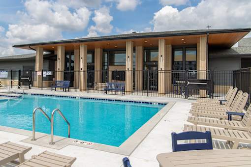 A pool with sun loungers and a building in the background.