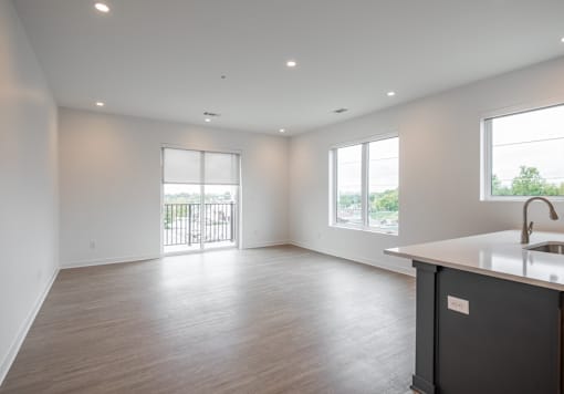 A spacious kitchen and living room with a wooden floor and white walls.