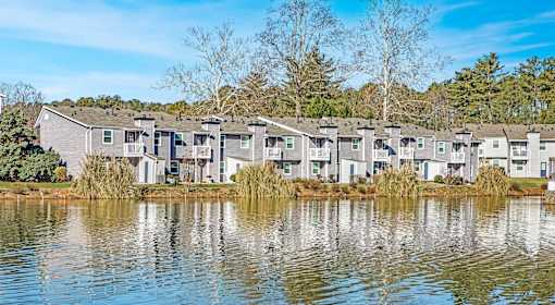 A row of houses are reflected in the water in front of them.