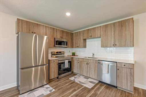A kitchen with wooden cabinets and a stainless steel refrigerator.