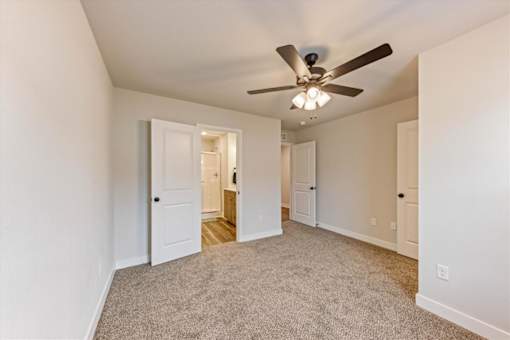 A room with a ceiling fan and carpeted floor.