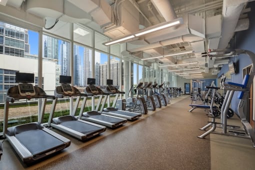 a gym with cardio machines and a view of the city
