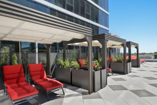 a patio with red chairs and potted plants in front of a building
