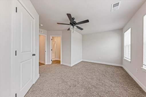 A room with a ceiling fan and carpeted floor.