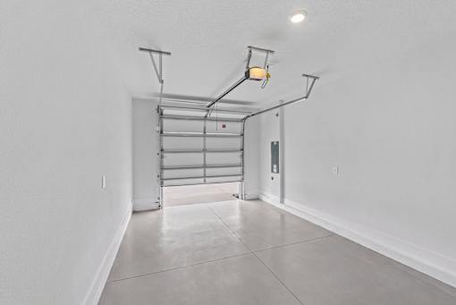 A white room with a grey floor and a grey wall with a white door.