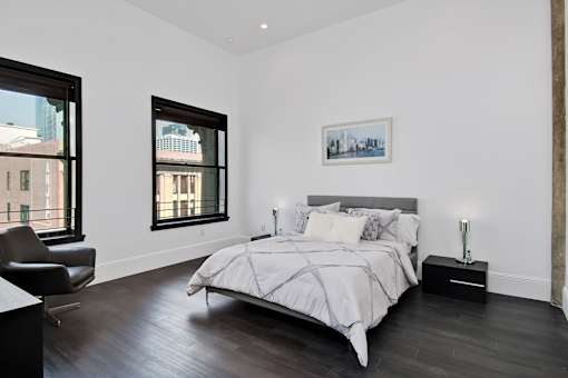 A bedroom with a large bed and a chair.