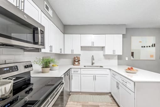 A modern kitchen with white cabinets and a black stove top.