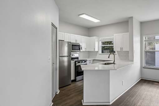A kitchen with white cabinets and a stainless steel refrigerator.