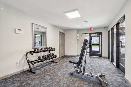 A gym room with a bench, weights, and a mirror.