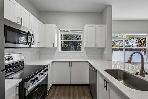 A kitchen with white cabinets and a black countertop.