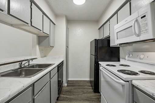 A kitchen with black and white appliances and a marble counter.