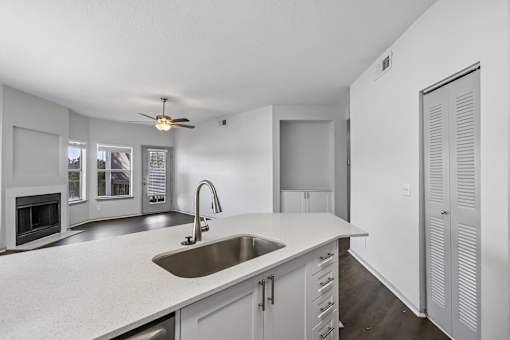 A modern kitchen with a white countertop and a stainless steel sink.