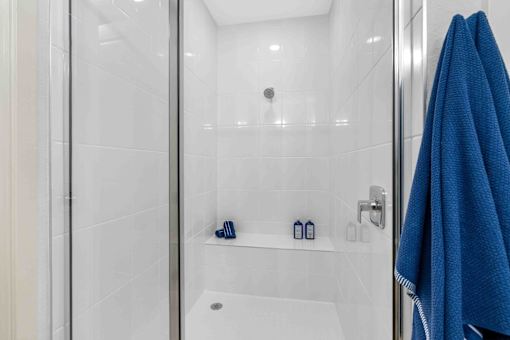 a bathroom with a shower and blue towels