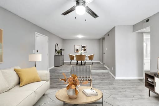 A living room with a white couch, a coffee table, and a dining table with chairs.