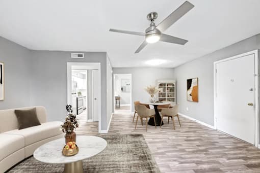 A living room with a couch, a table, and a ceiling fan.