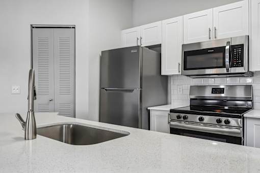 A modern kitchen with a stainless steel refrigerator, microwave, and oven.