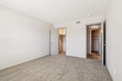 A room with a carpeted floor and two doors.
