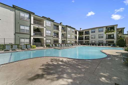 A large swimming pool is surrounded by apartment buildings.