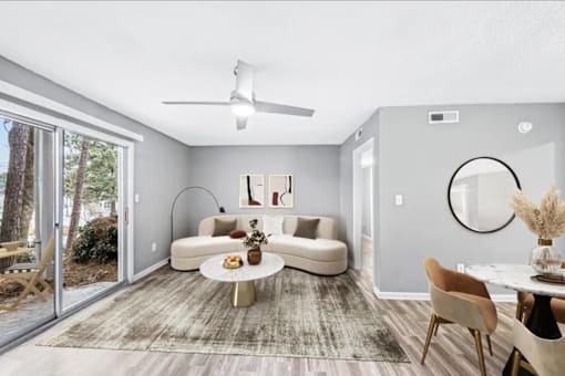 A modern living room with a white sofa, a round mirror, and a ceiling fan.