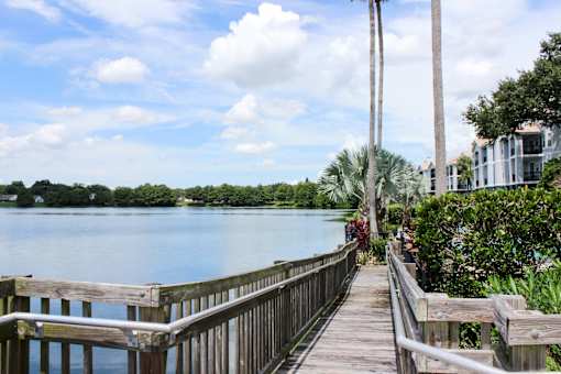 A wooden walkway leads to a body of water with a house on the right.
