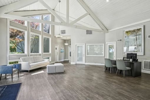 A spacious living room with a white sofa and a grey desk.