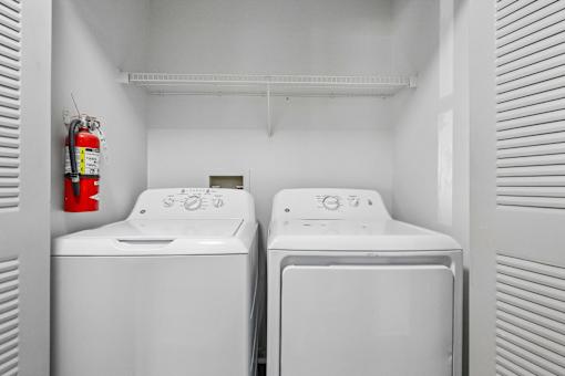 Two white washing machines in a small laundry room.