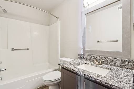 A bathroom with a granite countertop and a white bathtub.