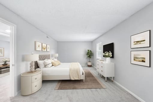 A bedroom with a white bed, nightstand, and chair.