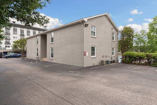 A grey building with a parking lot in front.