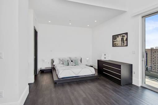 A bedroom with a large bed and a picture on the wall.