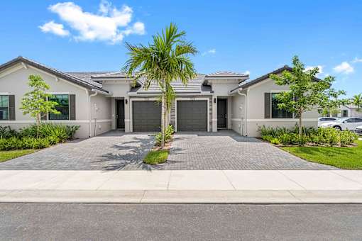 a house with a driveway and a palm tree in front of it
