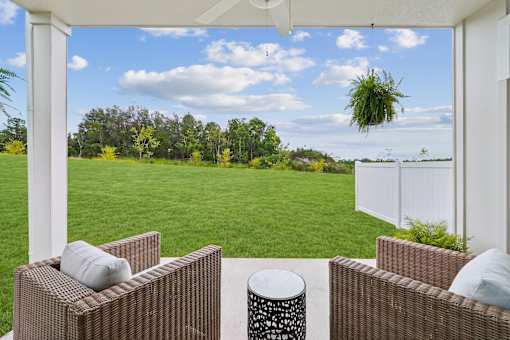 Two brown wicker chairs are placed on a patio with a table and a white pillow.
