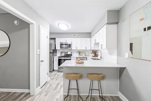 A modern kitchen with a white island and bar stools.