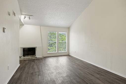 A large empty room with a fireplace and sliding glass doors.