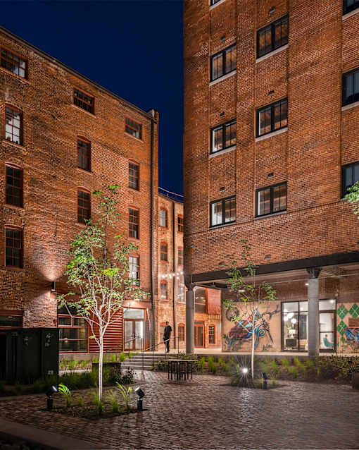 A courtyard between two red brick buildings with a tree in the center.