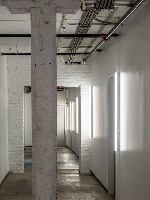 A long hallway with white walls and a concrete pillar.