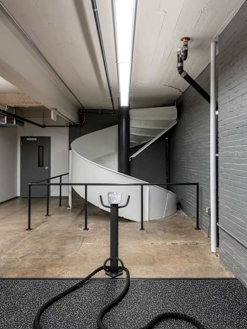 A spiral staircase in a building with a black railing and a black pole with a red light on top.