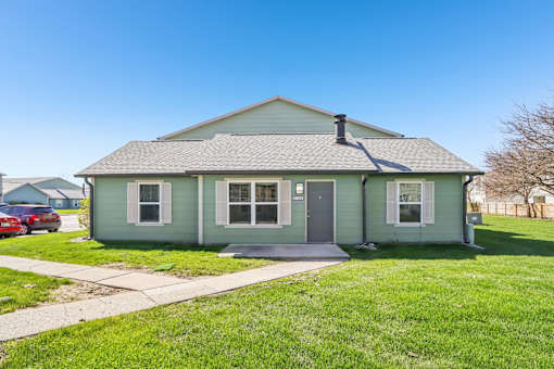 A small house with a grey roof and a green front.
