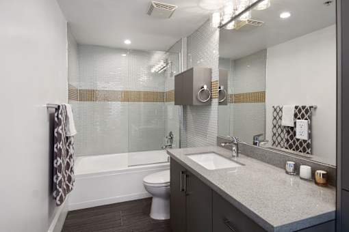 A bathroom with a toilet, sink, and a glass shower stall.