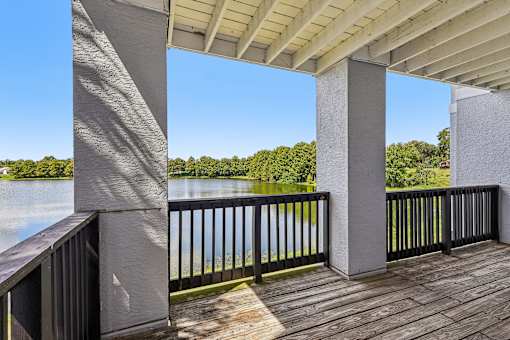 A wooden deck with a metal railing and a concrete pillar.